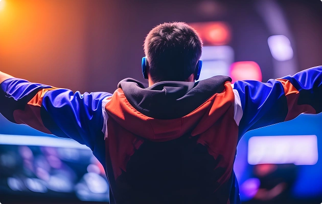 Een gamer met een koptelefoon op steekt zijn handen in de lucht om zijn overwinning te vieren tijdens een e-sporttoernooi met neonverlichting.