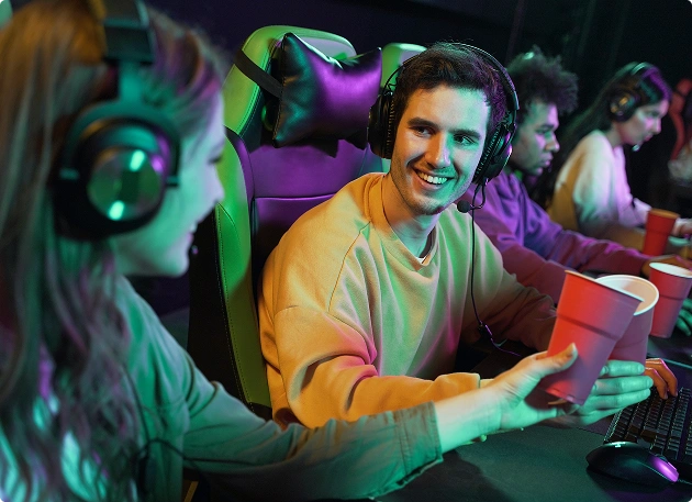 Een groep vrienden met gaming-koptelefoons zit achter de computer te gamen en praat met elkaar tijdens het online spelen.